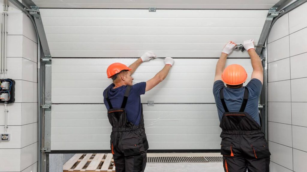 Mannen installeren een garagepoort in huis omdat dit vele voordelen brengt.