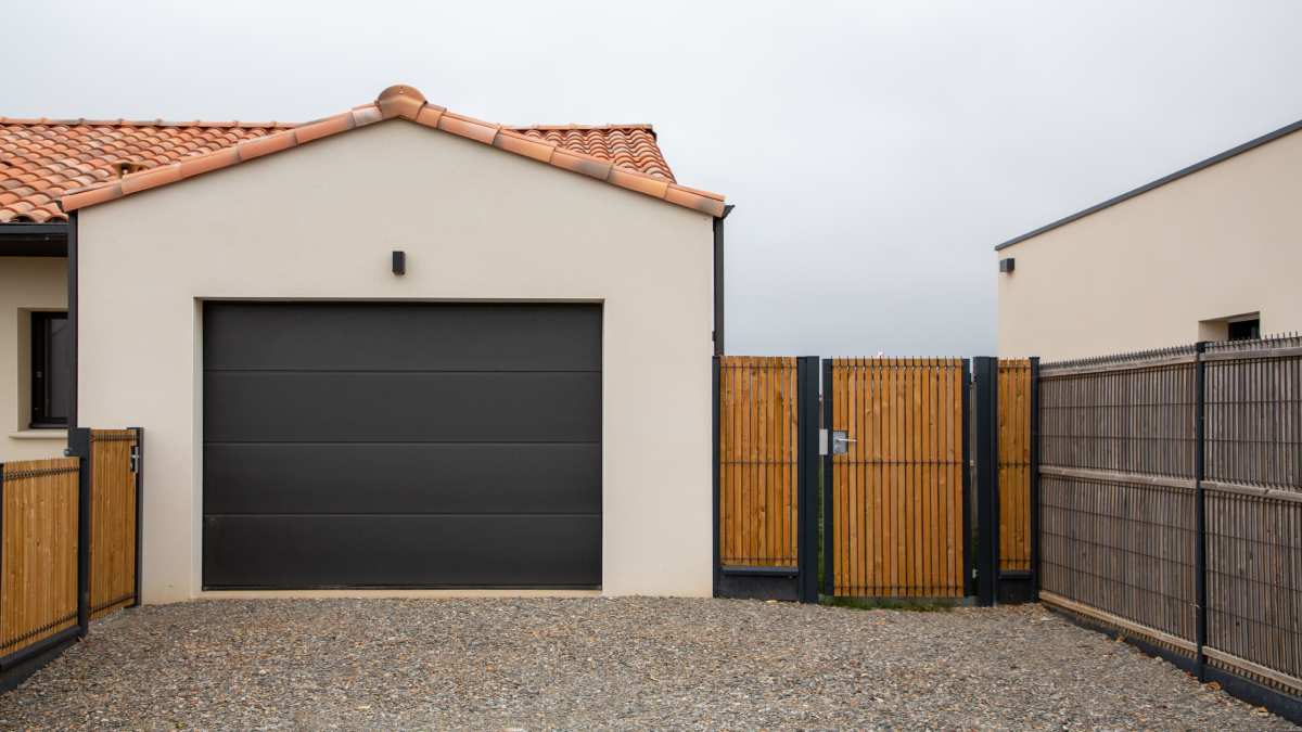 Zwarte aluminium garagepoort met witte muren er omheen.