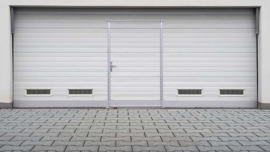 Een witte dubbele garagepoort uitgerust met een loopdeur.