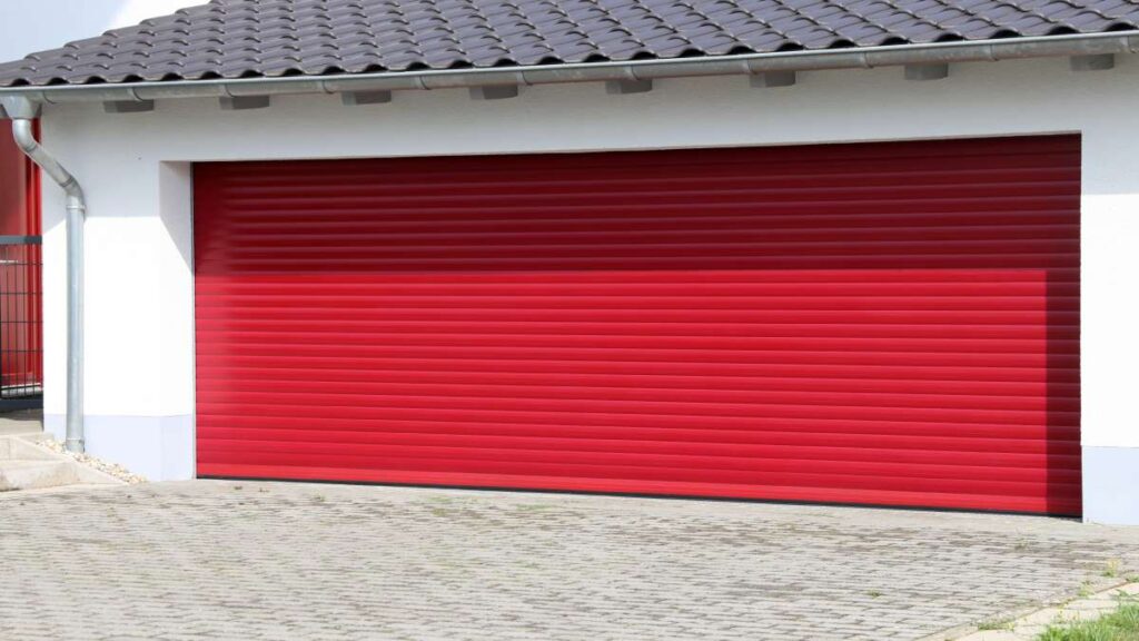 Wit huis met grote rode rollende pvc garagepoort.